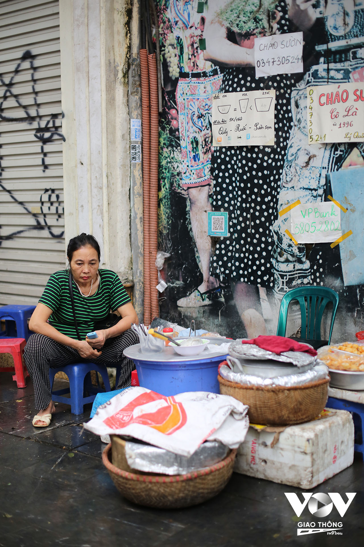 Một phụ nữ bán cháo quẩy trên phố Lý Quốc Sư tỏ ra mệt mỏi khi phải ngồi cả ngày bán hàng trên vỉa hè, dưới nắng nóng