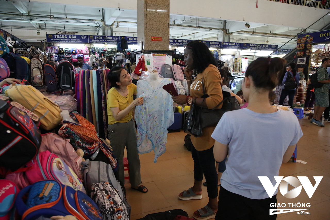 Một khách du lịch đang mặc cả chiếc áo lụa trong khu chợ chính Đồng Xuân. Chiếc áo người bán hàng muốn bán với giá 200 ngàn đồng...