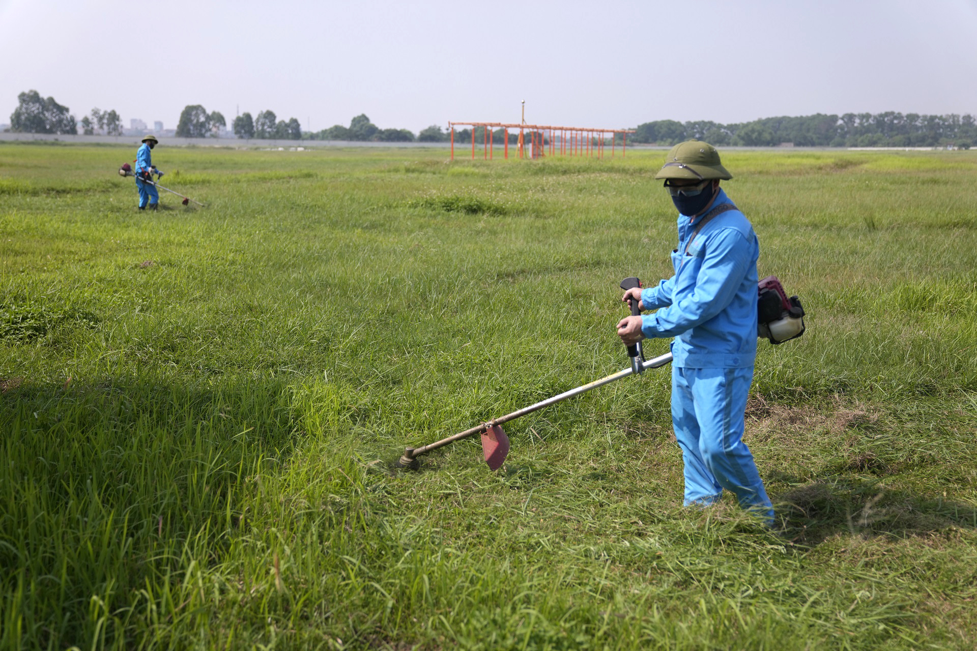 Nhân viên Đội vệ sinh môi trường khu bay miệt mài cắt cỏ