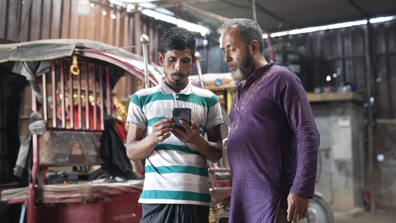 Ông Muhammad Delwar Hossain (phải) làm nghề lái xe tuk-tuk ở ngoại ô Thủ đô Dhaka của Bangladesh hơn một thập kỷ, bắt đầu chuyển sang sử dụng pin thông minh của công ty SOLshare vào năm ngoái. Ảnh: CNN