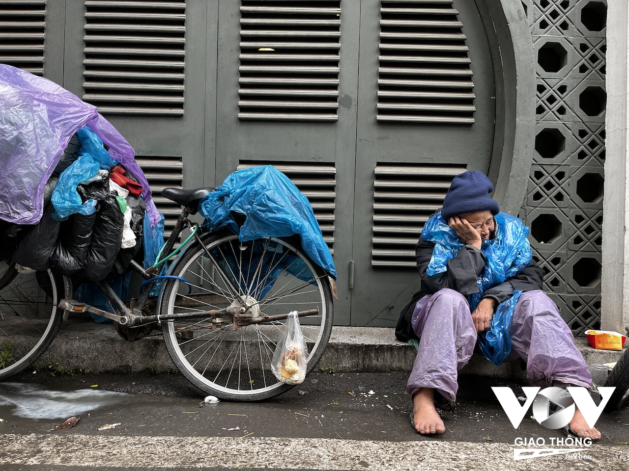 Một người vô gia cư ngồi ngủ gục trên vỉa hè phố cổ
