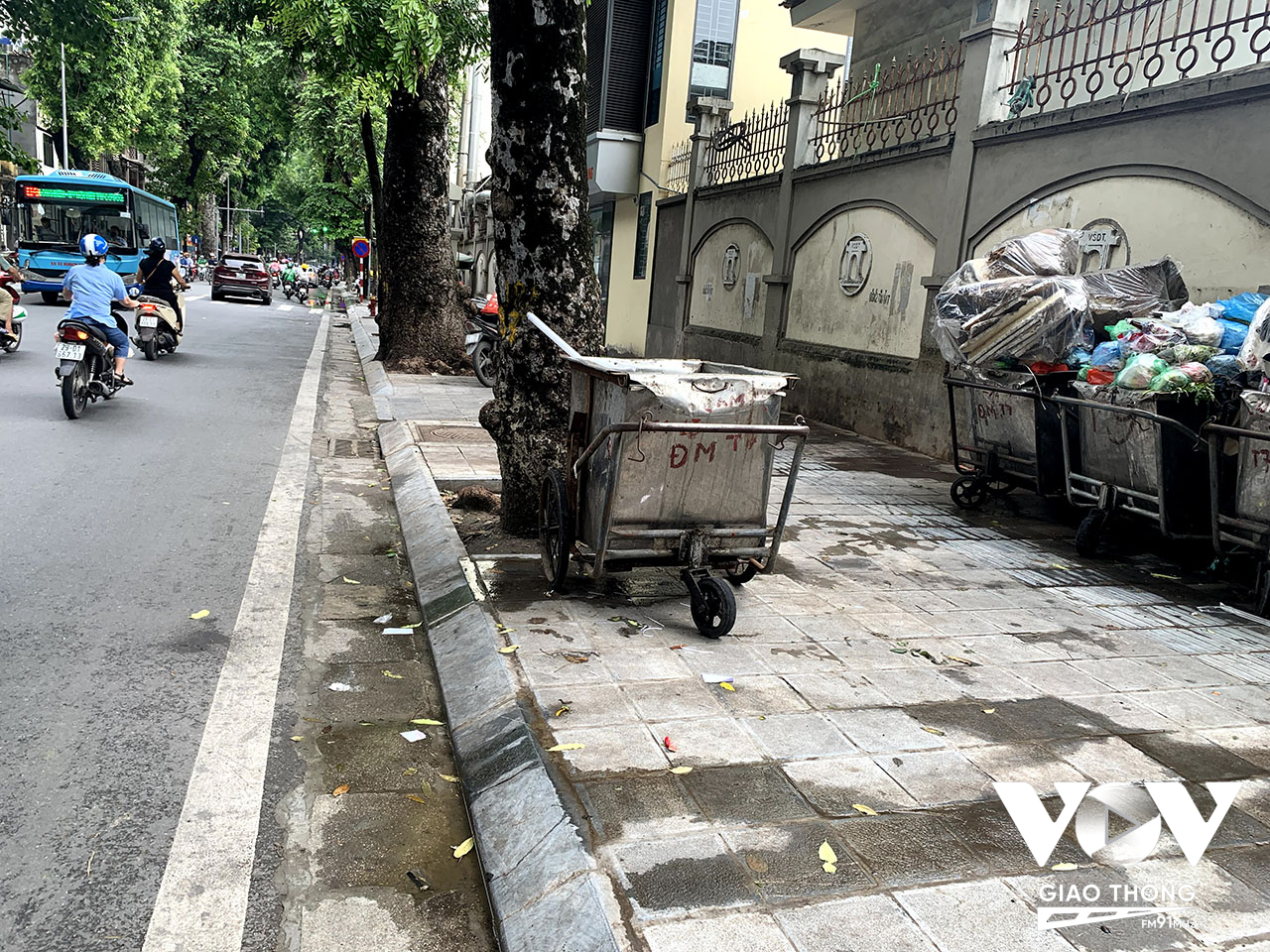 Nước thải chảy ra từ xe rác tràn từ vỉa hè xuống lòng đường ở một bãi tập kết rác thải trên phố Lò Đúc