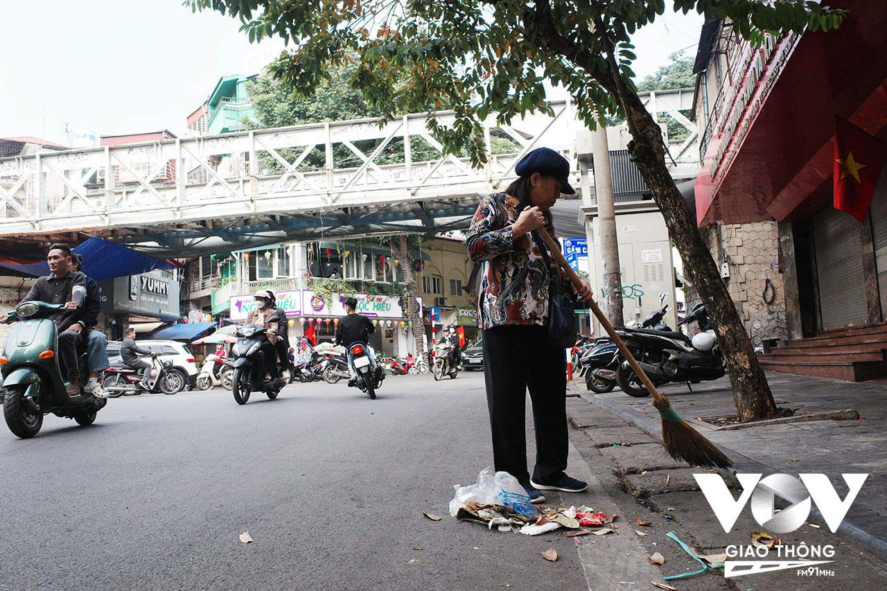 Một bà cụ quét rác trên đường sáng sớm đầu năm, dù không phải việc của mình nhưng đây vẫn là thói quen giữ gìn vệ sinh chung của nhiều người dân Hà Nội