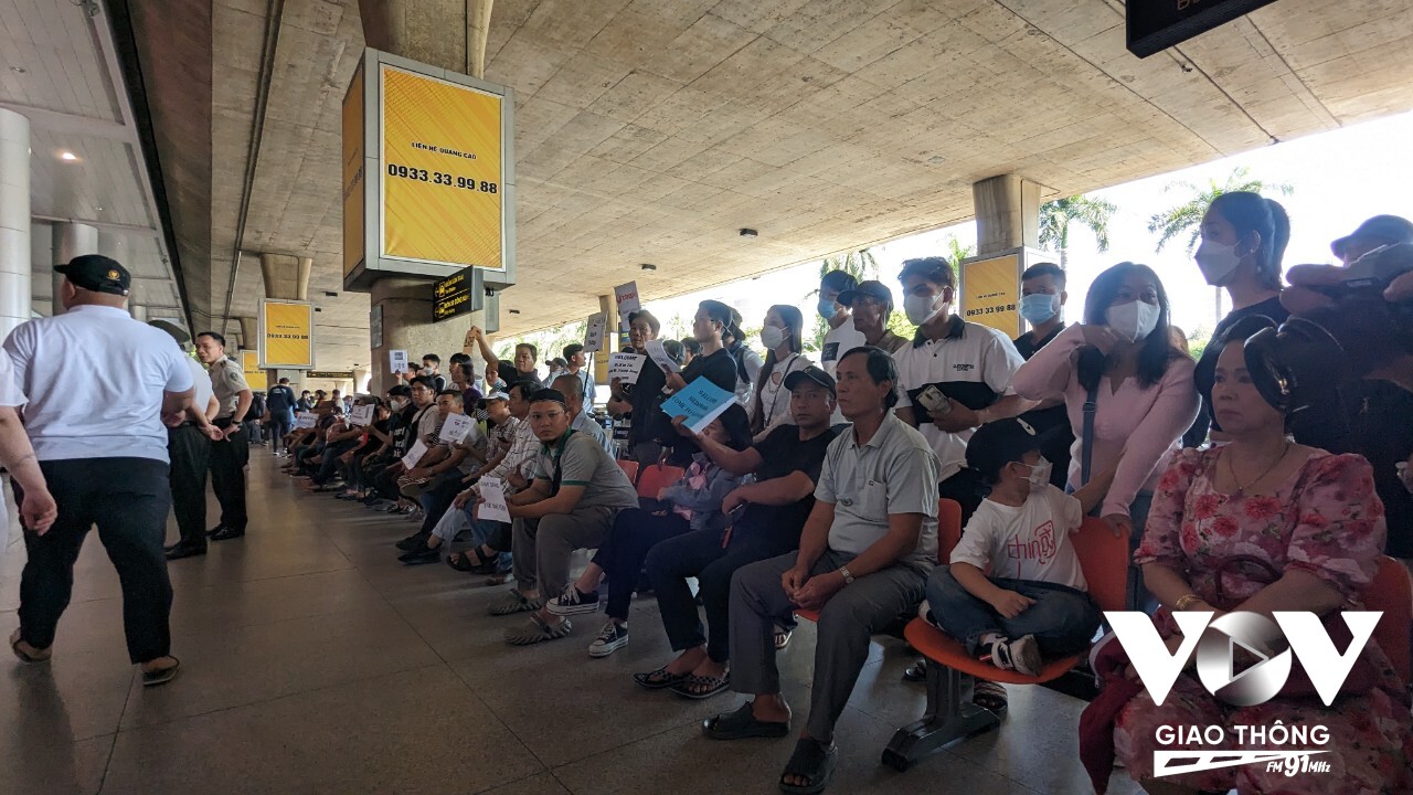 Hàng dài người thân ngồi trước khu vực ga đến dõi mắt chờ người thân hoàn thành các thủ tục nhập cảnh