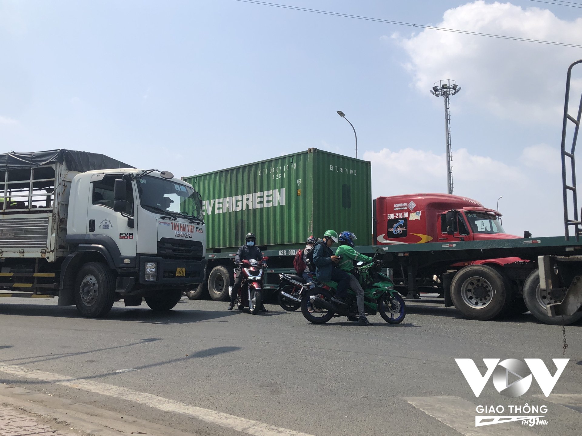 Dòng phương tiện container và xe máy phải chen chúc để có thể di chuyển qua khỏi nút giao vòng xoay Phú Hữu, TP. Thủ Đức TPHCM, d