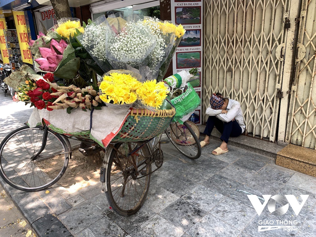 Người phụ nữ bán hoa tươi tranh thủ chợp mắt trước hiên nhà một cửa hàng đóng cửa nghỉ trưa trên phố Hàng Điếu giữa cái nóng trưa hè