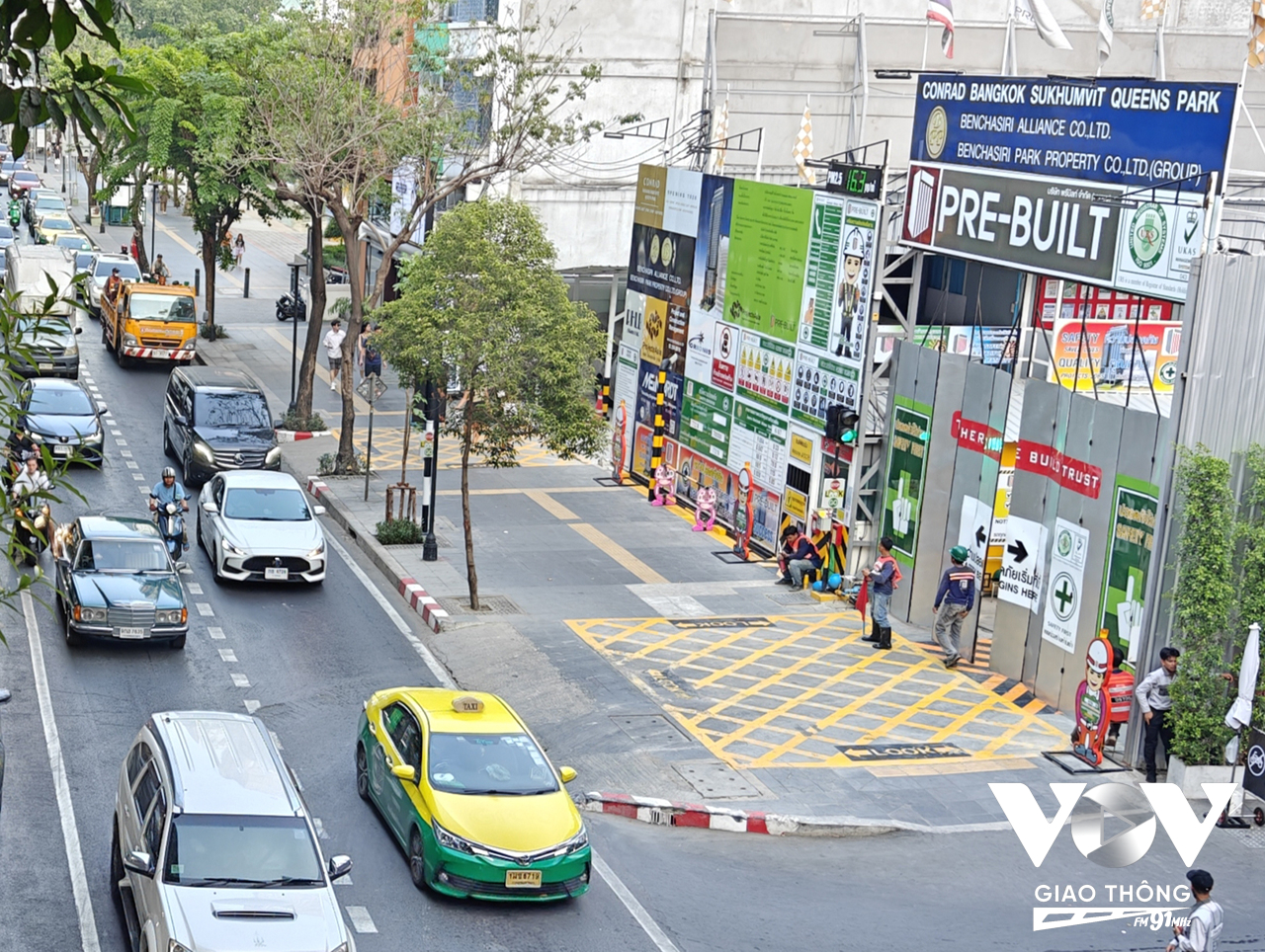 Một mô hình cảnh báo cho người đi bộ khi ngang qua công trường tại Thái Lan với vạch kẻ vàng, chữ lớn và có người ứng trực