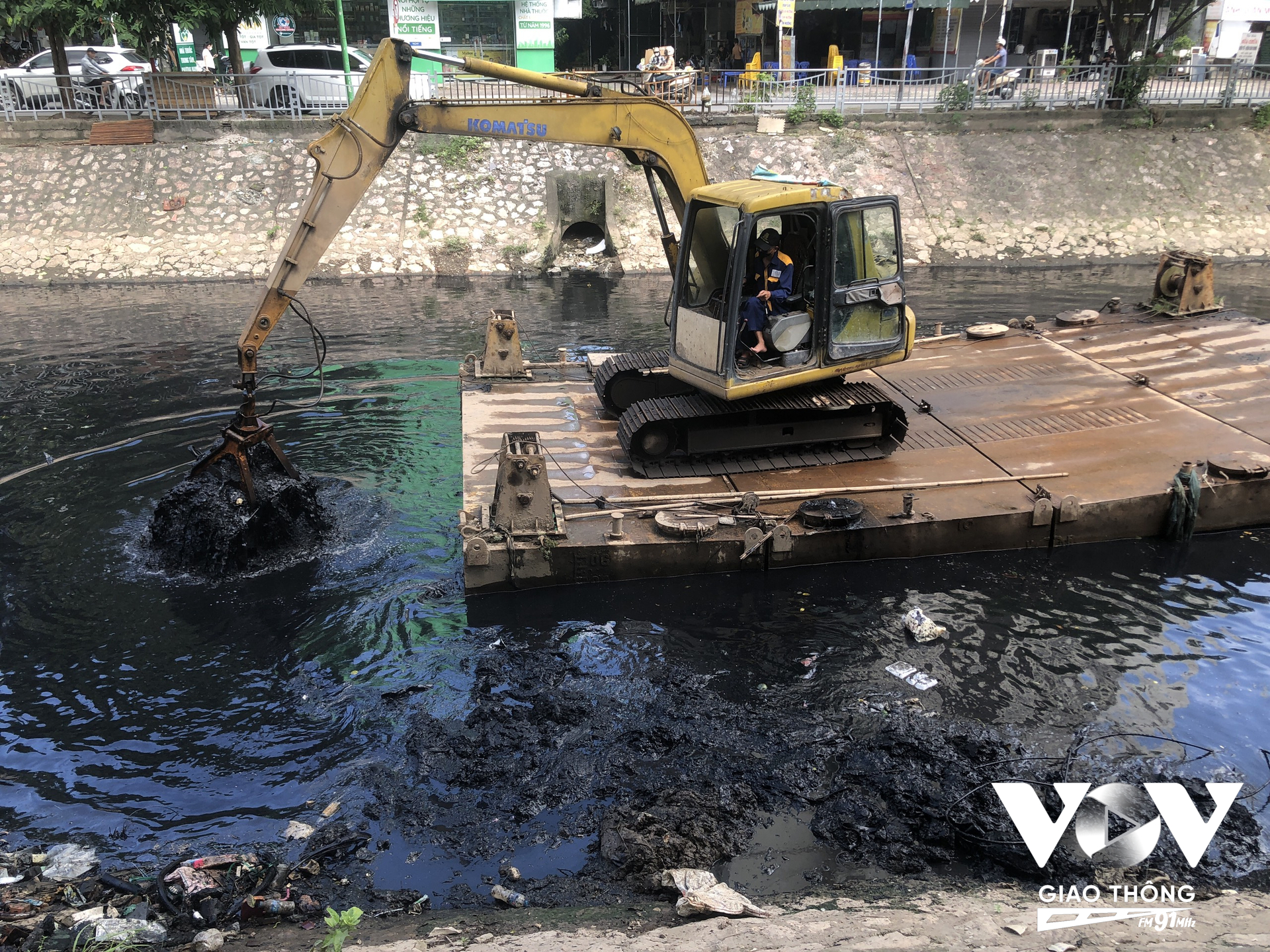 Máy xúc thu gom bùn và rác thải chuyển lên xe chứa