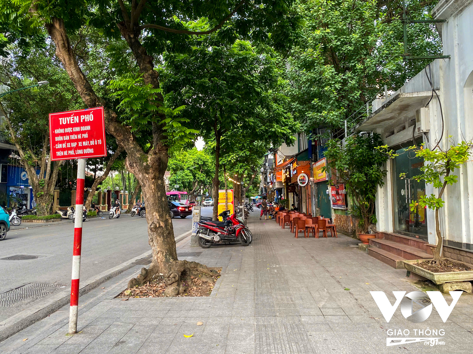 Mặc dù có các biển cấm 'Không được kinh doanh buôn bán trên hè phố' nhưng đằng sau tấm biển, tại vị trí 21 Trần Phú một quán bia vẫn vô tư bày biện bàn ghế trên vỉa hè.