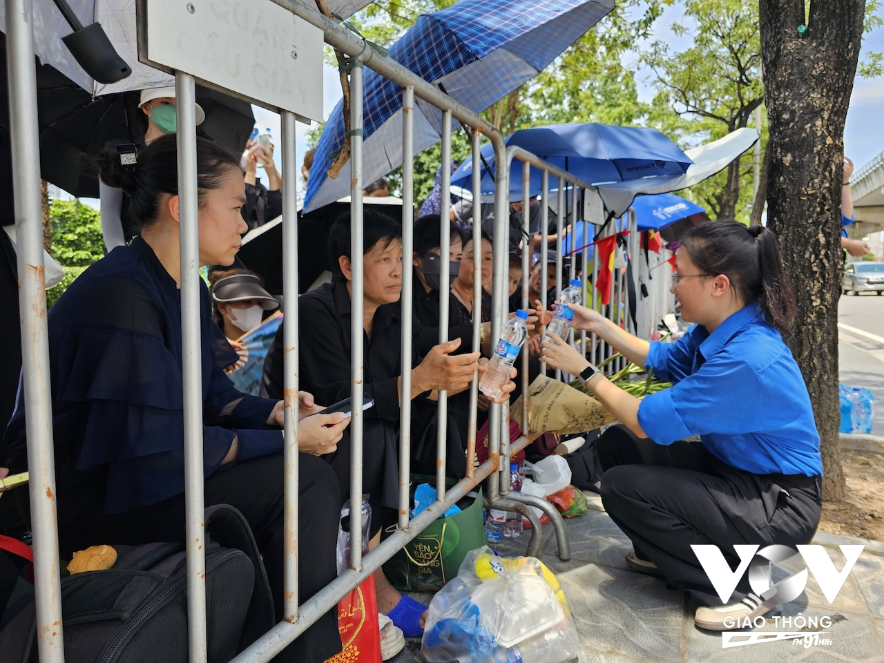 Nhiều người dân đã có mặt tại gần khu vực Nghĩa trang Mai Dịch để đưa tiễn cố Tổng Bí thư Nguyễn Phú Trọng. Lực lượng chức năng đảm bảo an ninh trật tự, các thanh niên tình nguyện cấp phát nước cho người dân trong lúc chờ đợi (Ảnh: Hải Bằng)