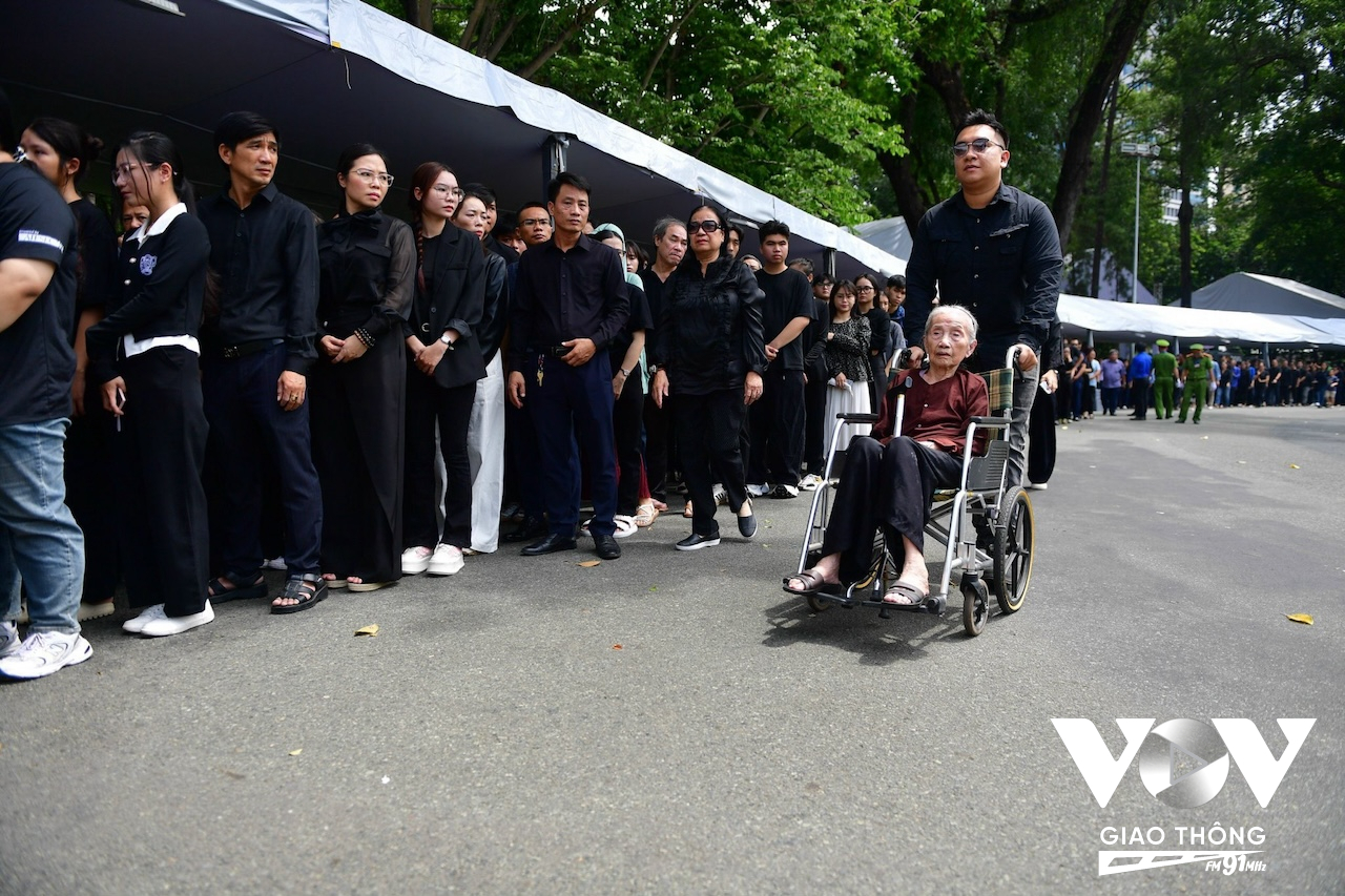 Một cụ bà đi xe lăn được tình nguyện viên hỗ trợ vào viếng cố Tổng Bí thư tại Hội trường Thống nhất vào những giờ phút cuối cùng. (Ảnh: Phan Nhơn)