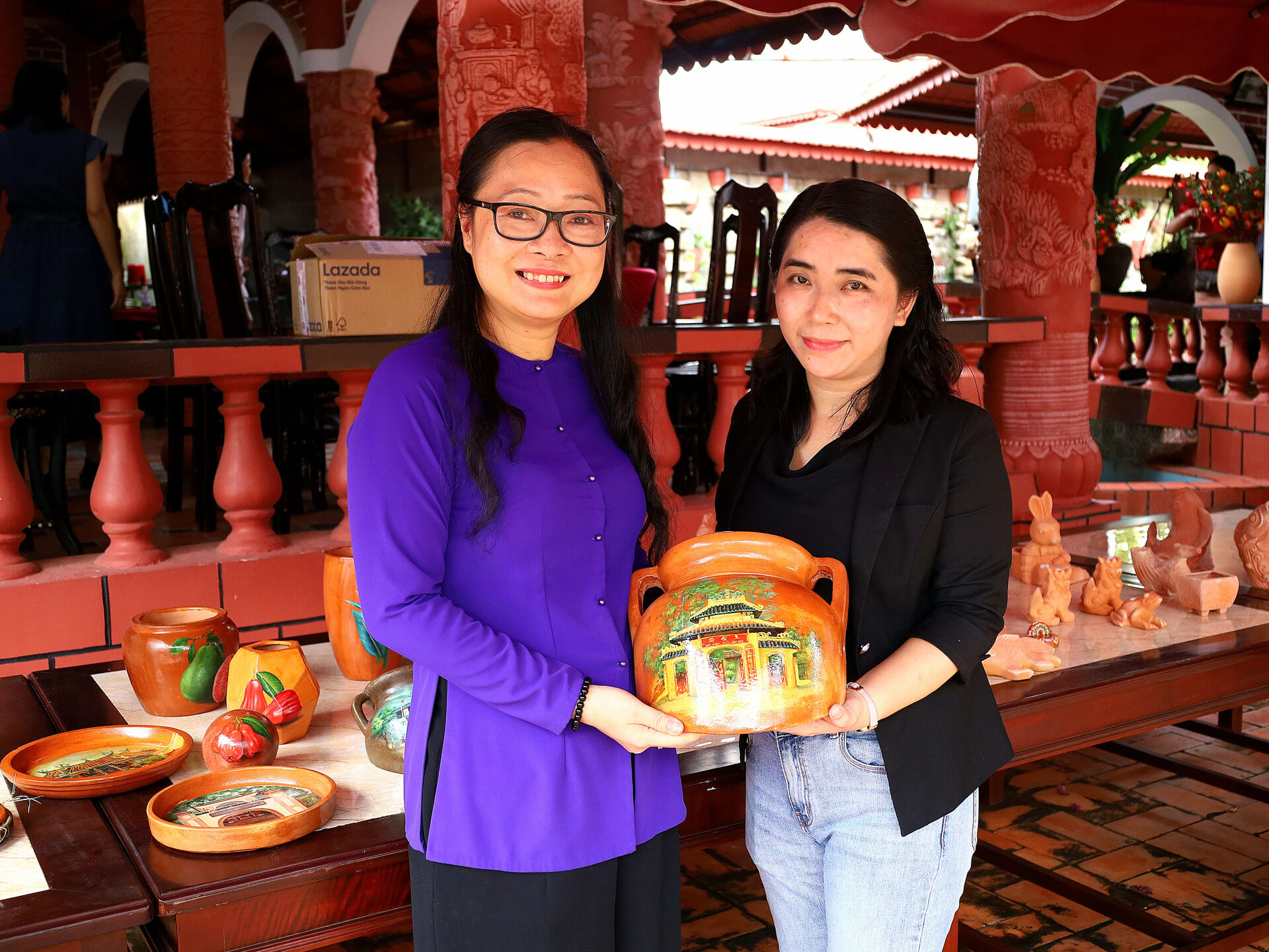 Chị Hồ Thanh Thảo (phải) mạnh dạn khởi nghiệp từ việc vẽ tranh lên sản phẩm gốm đỏ làm quà lưu niệm. Ảnh: NVCC