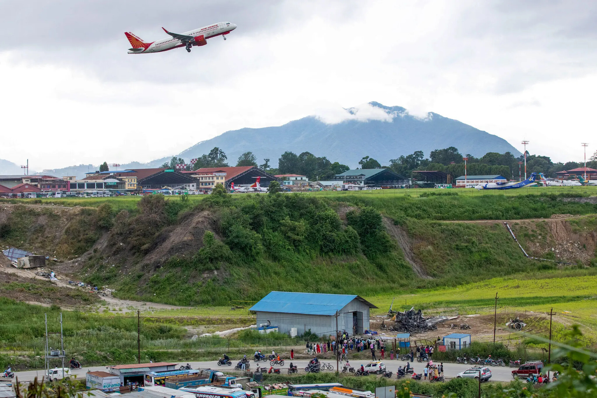 Một chiếc máy bay bay qua đống đổ nát của máy bay Saurya Airlines tại Kathmandu, Nepal. (Ảnh: Getty Images)