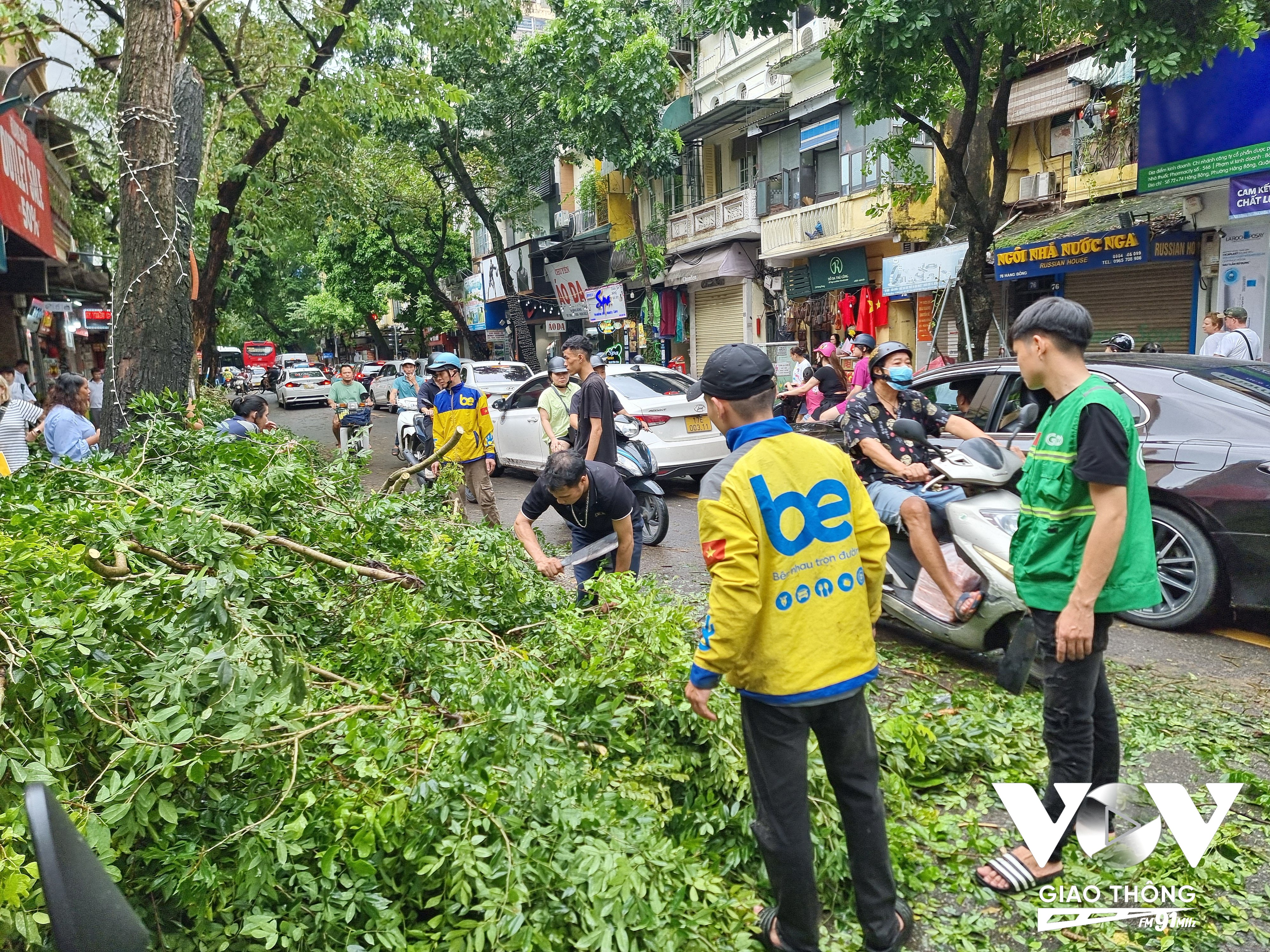 Một nhóm bạn trẻ làm nghề xe ôm công nghệ xử lý các cành, cây gãy đổ trên phố Hàng Bông (Hoàn Kiếm, Hà Nội).