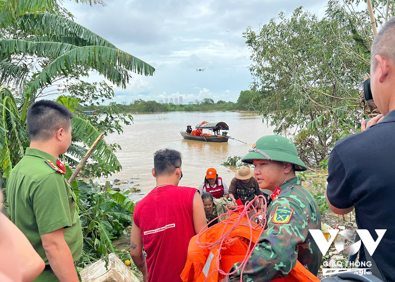 Lực lượng chức năng huy động thuyền đưa người dân bị mắc kẹt từ bãi giữa sông Hồng vào bờ