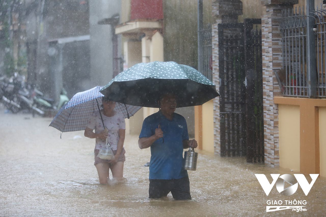 Người dân phải đội mưa, lội nước đi mua những mặt hàng thiết yếu như cơm và nước sinh hoạt