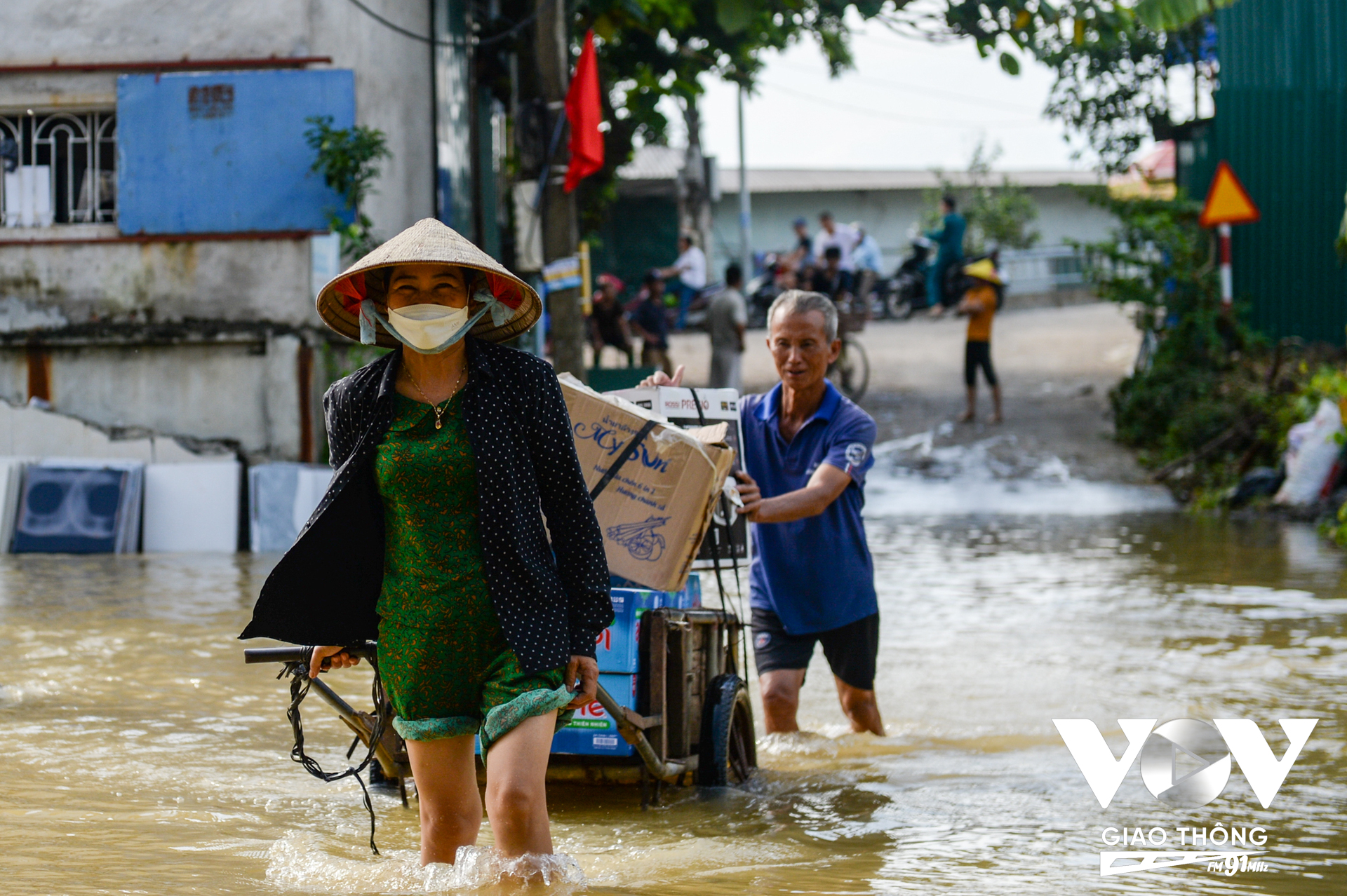 Người dân di chuyển nước sạch từ con đường đầu làng, sau khi kéo qua chỗ ngập nông dưới 60cm sẽ chuyển đồ lên thuyền để vận chuyển về nhà.