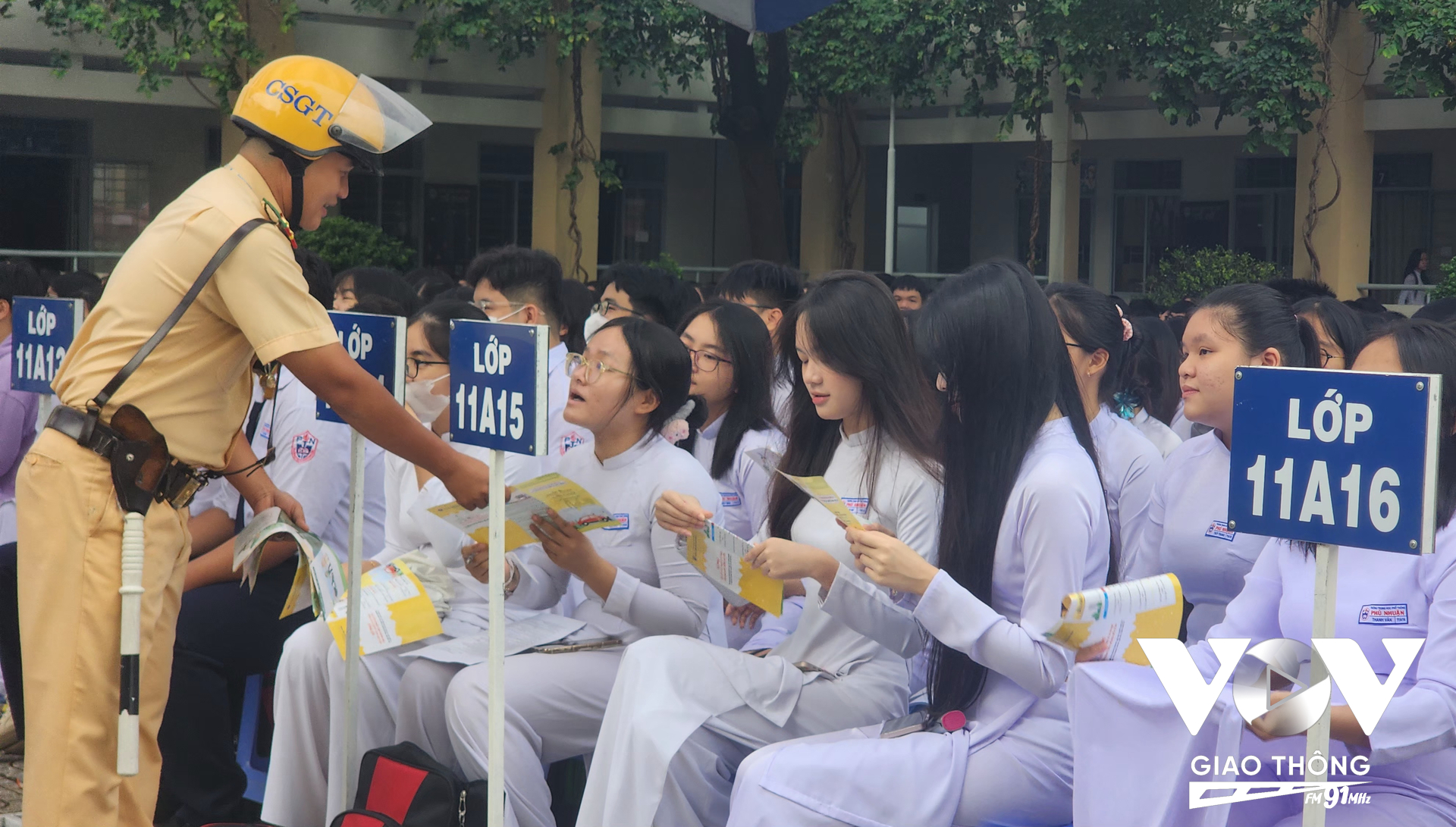 Cán bộ, chiến sĩ CSGT phát tờ rơi cho các em học sinh trong buổi tuyên truyền phổ biến pháp luật giao thông đường bộ