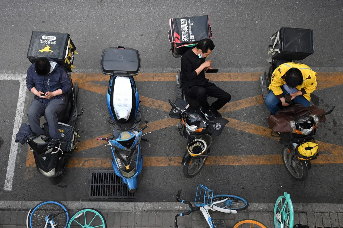 Các nhân viên giao thức ăn chờ nhận đơn bên ngoài một nhà hàng ở Bắc Kinh. Ảnh: Greg Baker/AFP/Getty Images.