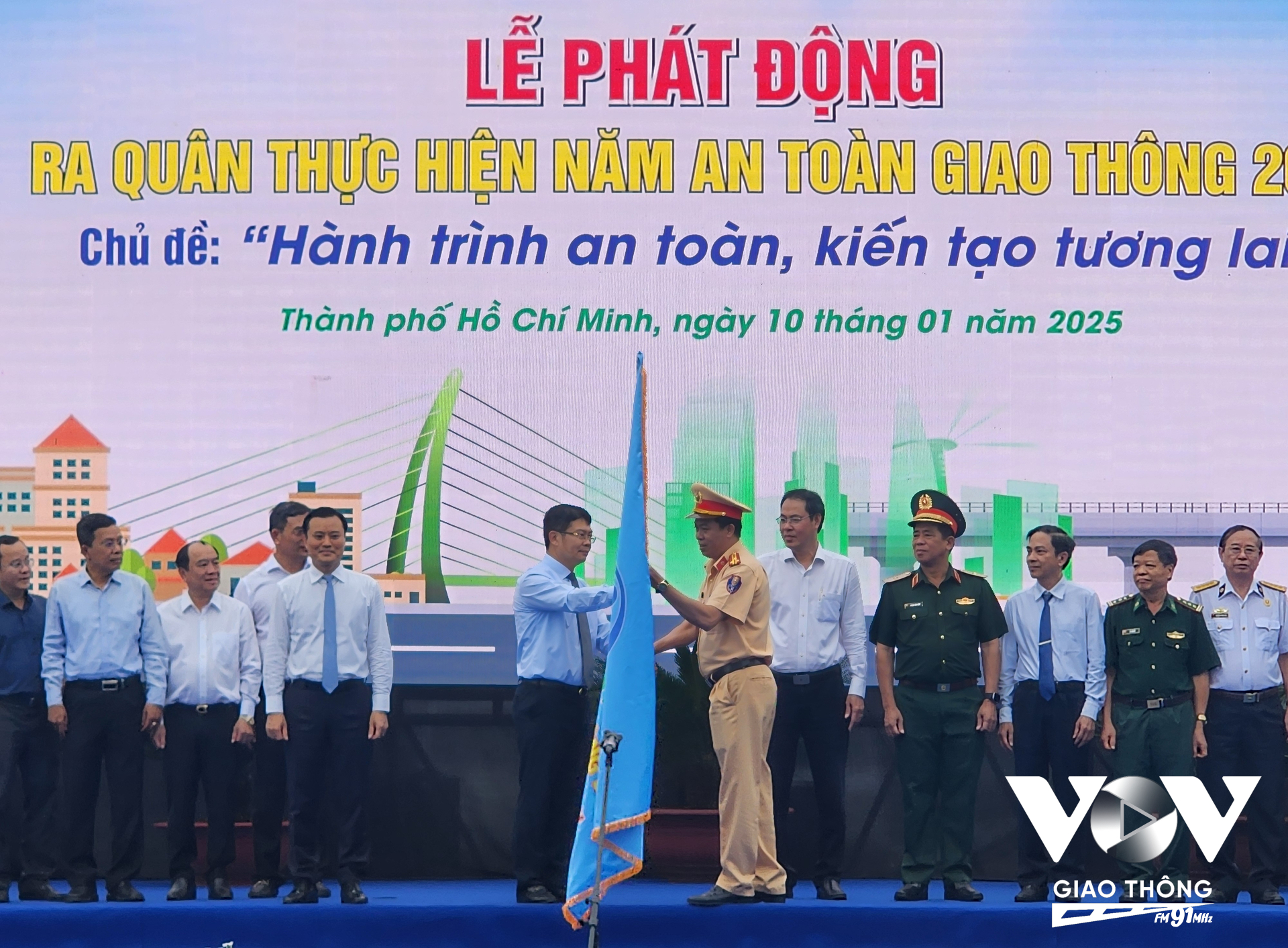 Ông Nguyễn Thành Lợi, Phó Ban chuyên trách Ban An toàn giao thông Thành phố Hồ Chí Minh, trao cờ phát động Năm An toàn giao thông 2025 cho Thượng tá Trần Trung Hiếu, Trưởng phòng CSGT Công an TP.HCM