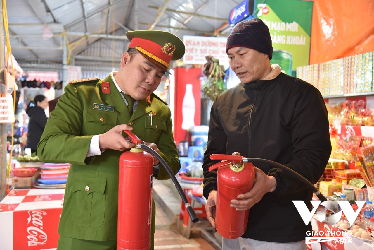 Thượng úy Hà Hồng Sơn - Cán bộ Đội Cảnh sát PCCC&CNCH Công an huyện Mỹ Đức hướng dẫn sử dụng bình chữa cháy tại chỗ cho các hộ kinh doanh tại Chùa Hương