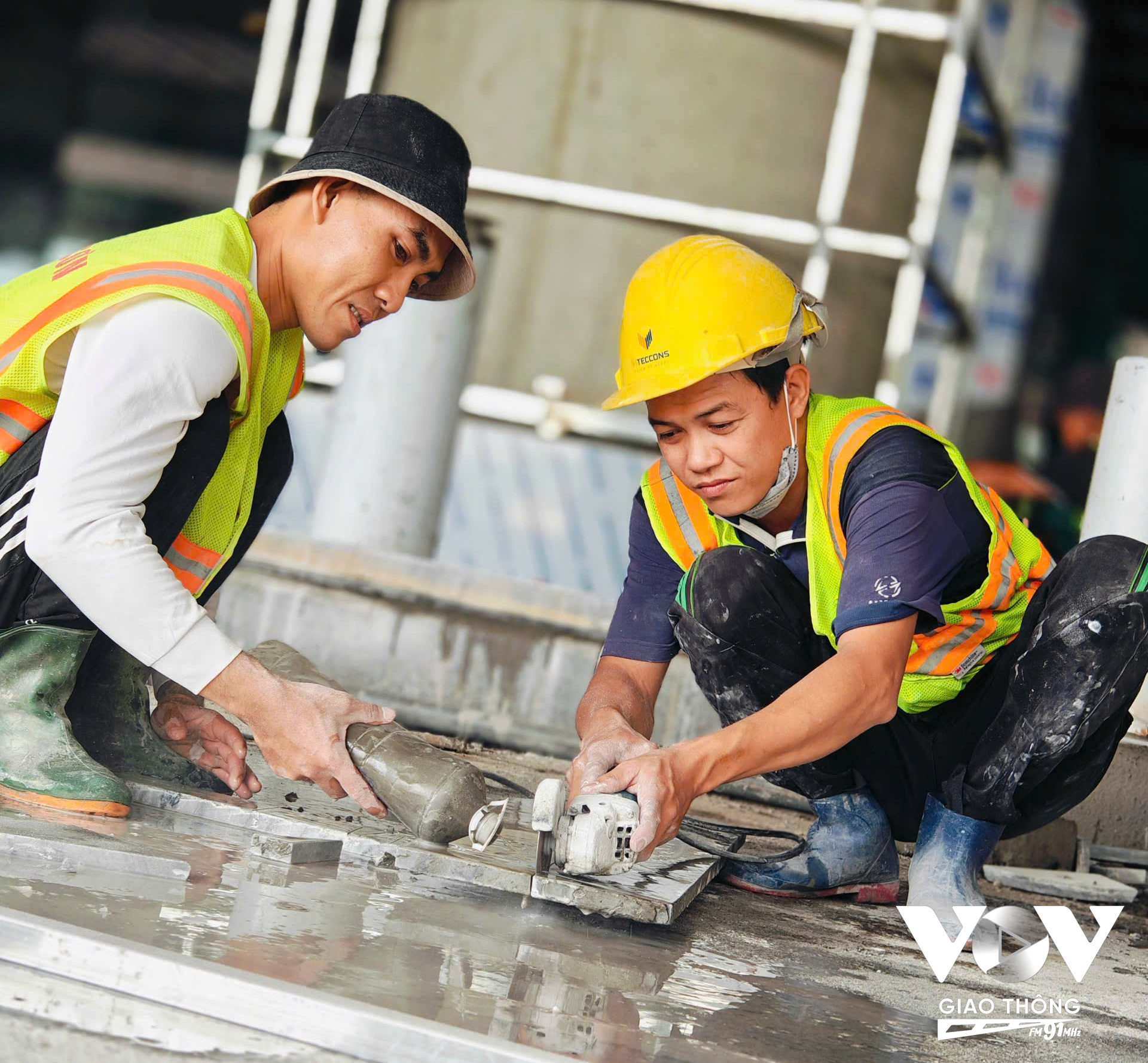 Một nhóm công nhân khác đang thi công cắt đá để hoàn thiện khu vực bên ngoài sảnh đi