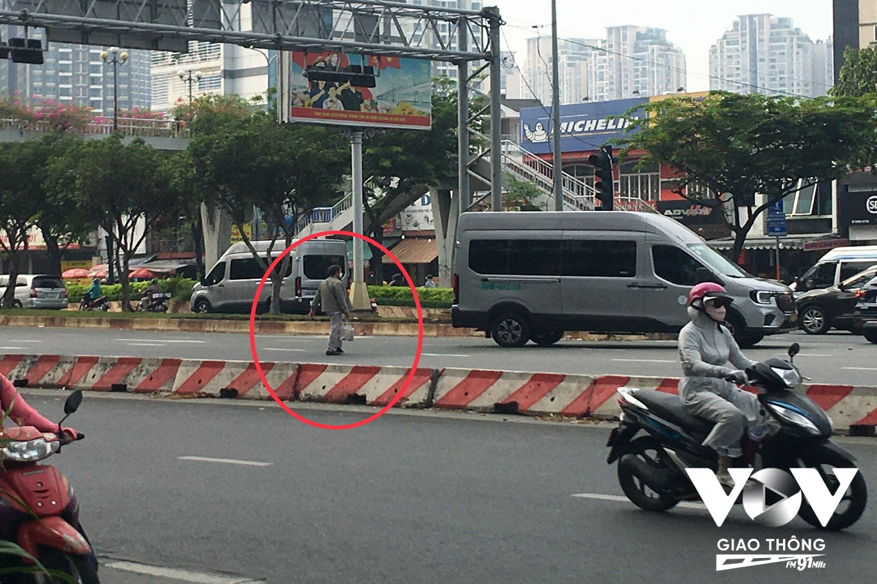 Người dân đi bộ băng qua đường Điện Biên Phủ mặc dù cầu dành cho người đi bộ cách đó vài chục mét