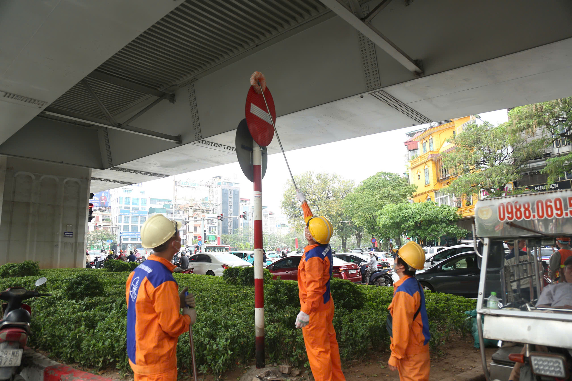 Các công nhân thuộc Công ty CP Công trình giao thông Hà Nội thực hiện vệ sinh cột biển báo để người dân dễ dàng quan sát