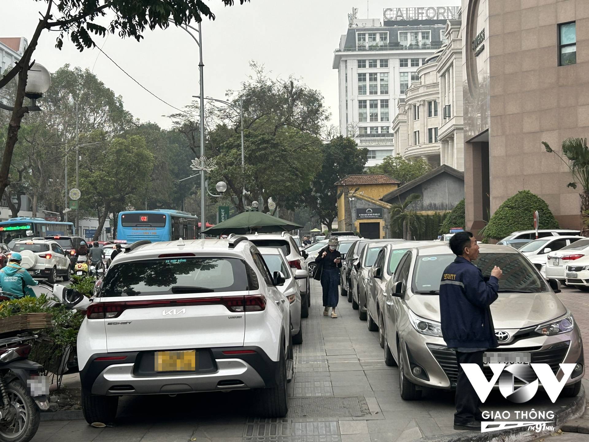 Người đi bộ len lỏi giữa hàng ô tô dừng đỗ tại phố Hai Bà Trưng