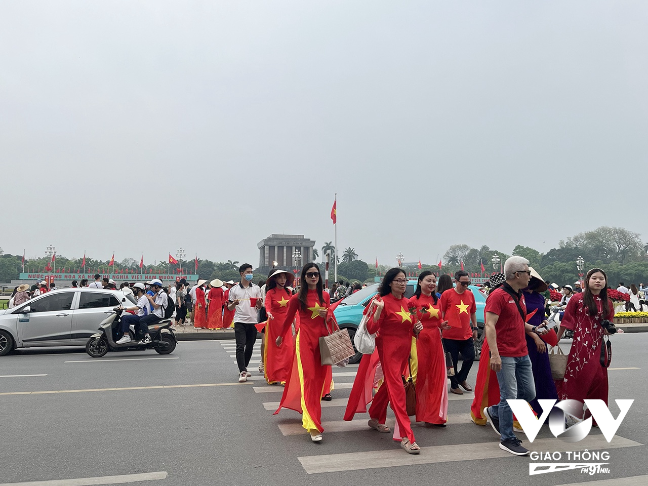 Nhiều người mặc áo dài, cầm cờ Tổ quốc cùng nhau ra quảng trường Độc lập trước Lăng Bác Hồ chụp ảnh kỷ niệm trong những ngày tháng Tư lịch sử này