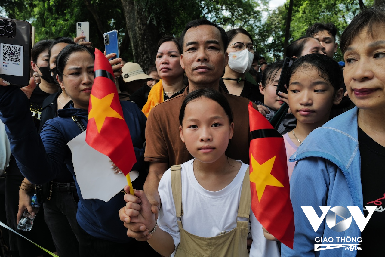 Em bé cầm cờ trong đoàn người nối dài đưa tiễn linh cữu cố Tổng Bí thư Nguyễn Phú Trọng.