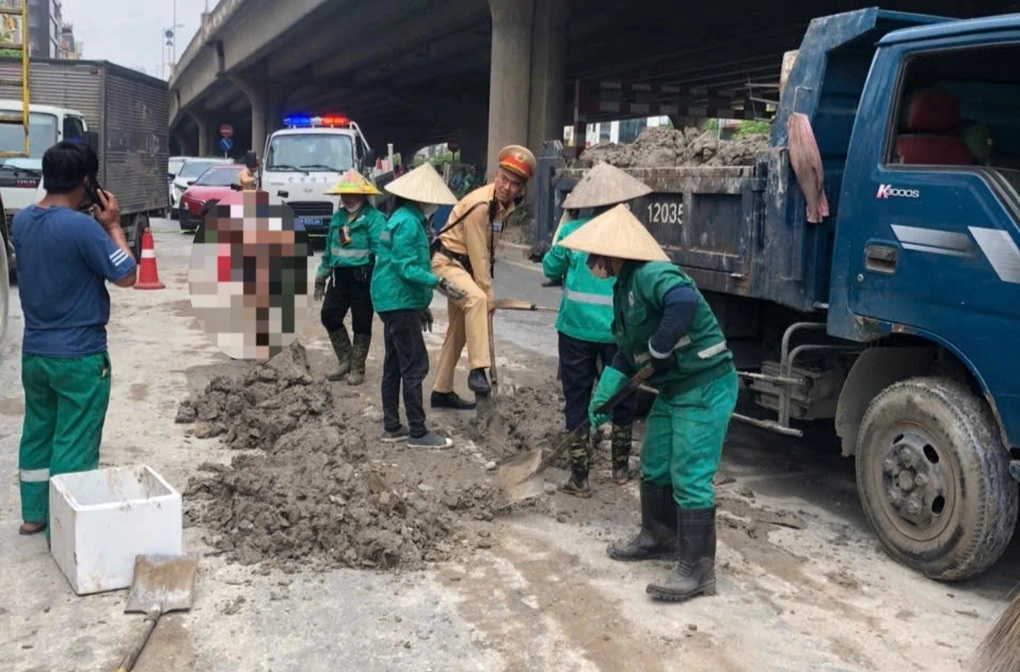 CSGT cùng nhân viên môi trường dọn dẹp đống bùn đất bị rơi vãi trên đường Nguyễn Xiển (Ảnh: Công an cung cấp).