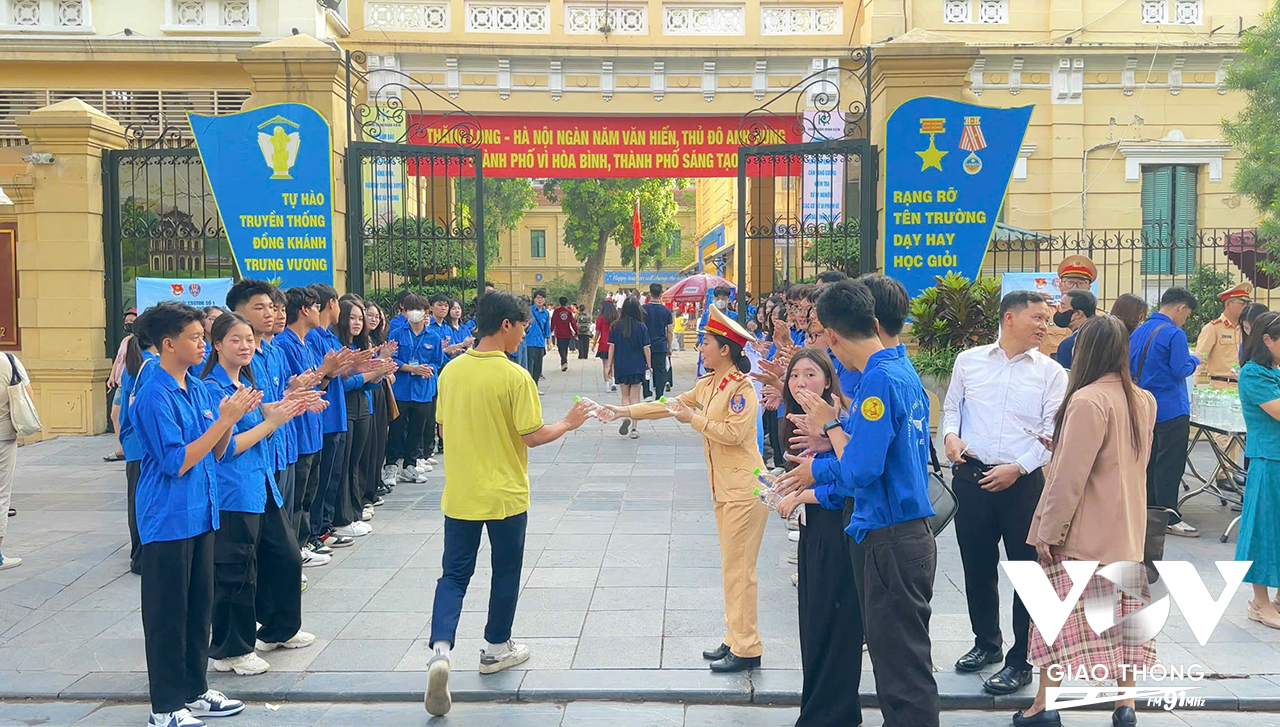 Cán bộ Đội CSGT đường bộ số 1 tiếp nước cho thí sinh tại điểm thi THCS Trưng Vương (quận Hoàn Kiếm)
