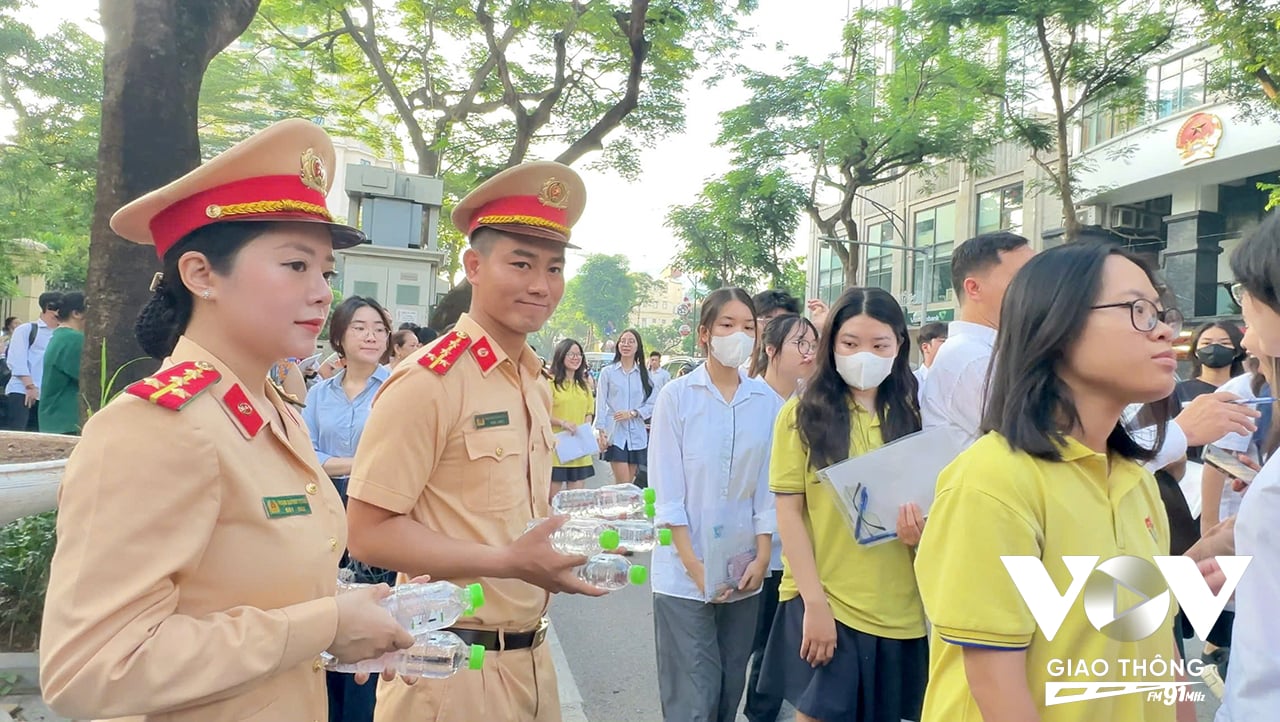 Cán bộ Phòng CSGT Hà Nội phát nước uống cho các thí sinh vào phòng thi tại THCS Trưng Vương - Hoàn Kiếm, một trong 5 điểm thi của Hoàn Kiếm (Hà Nội)