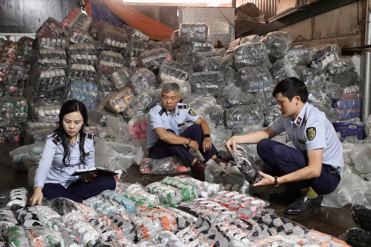 Cơ quan chức năng kiểm đếm kho hàng gần 10.000 đôi tất giả tại một công ty ở xã La Phù, Hoài Đức, Hà Nội. Ảnh: DMS