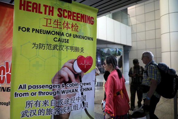 Hành khách đi qua tấm banner cung cấp thông tin về dịch viêm phổi cấp ở Vũ Hán tại điểm rà quét thân nhiệt tại ga đến quốc tế ở sân bay Kuala Lumpur - Ảnh: REUTERS