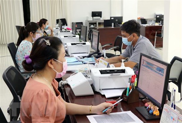 Cán bộ công chức Trung tâm Phục vụ hành chính công tỉnh Ninh Thuận giải quyết hồ sơ, thủ tục hành chính cho các doanh nghiệp. (Ảnh: Công Thử/TTXVN)