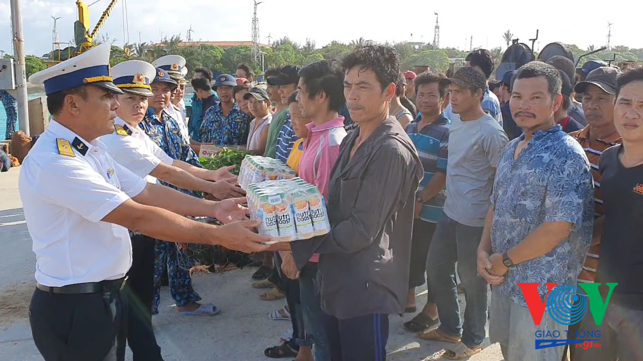 Cán bộ Trung tâm Hậu cần - Kỹ thuật đảo Sinh Tồn tặng quà cho các ngư dân gặp nạn trước khi lên tàu KN 410 về đất liền
