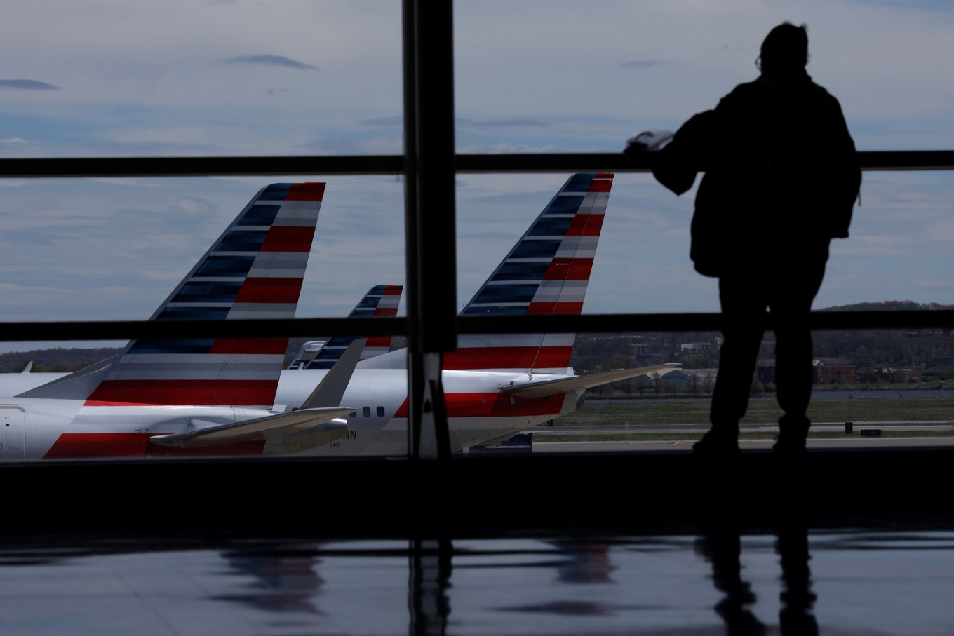 Một hành khách quan sát những chiếc máy bay của American Airlines tại sân bay quốc tế Washington Reagan