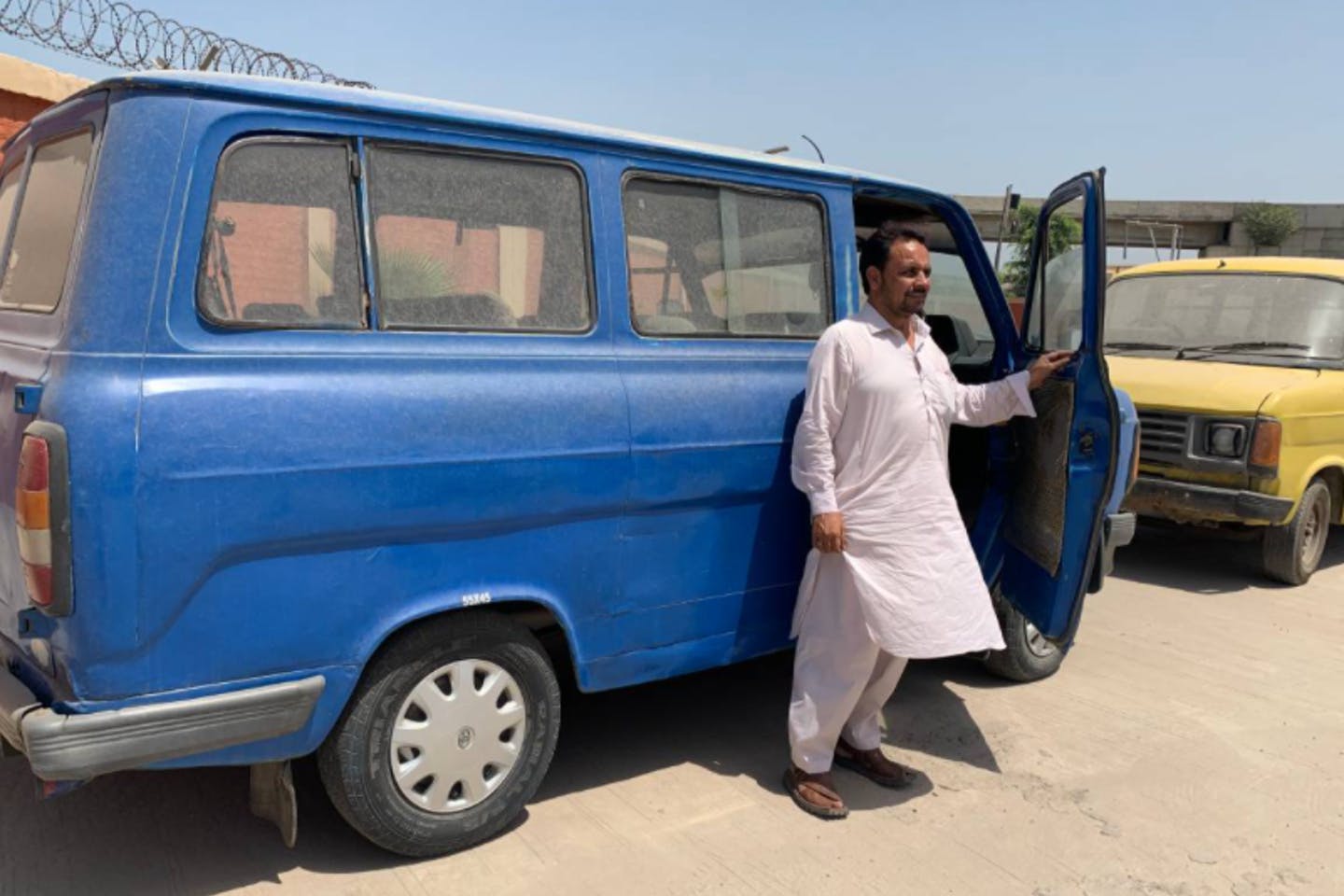 Mukhtiar Ahmed đứng bên một chiếc xe khách cũ ở Peshawar, Pakistan - Ảnh  Thomson Reuters Foundation