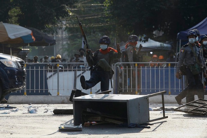 Cảnh sát đá vào rào chắn người biểu tình dựng lên tại một con đường ở Yangon ngày 2/3. Ảnh: Reuters.