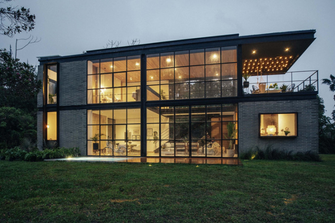 Ngôi nhà 2 tầng nổi bật với những khung thép tối màu và hệ thống cửa kính cho phép nhìn xuyên thấu bên trong.