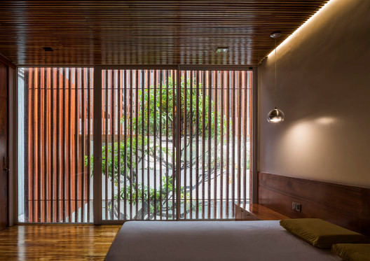 Phòng ngủ mát mẻ nhờ hệ lam gỗ và cây xanh phía ngoài. Nguồn ảnh: Archdaily.