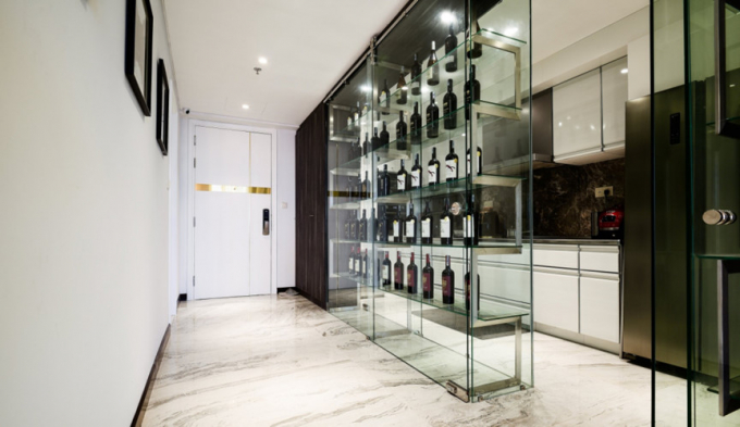 Chủ nhà có sở thích sưu tầm rượu, kiến trúc sư đã khéo léo biến vách ngăn bếp thành hệ tủ rượu bằng kính. Cách kết hợp này vừa để ngăn cách không gian nấu ăn với phòng khách, vừa biến vách ngăn thô cứng thành một tủ rượu khá độc đáo.