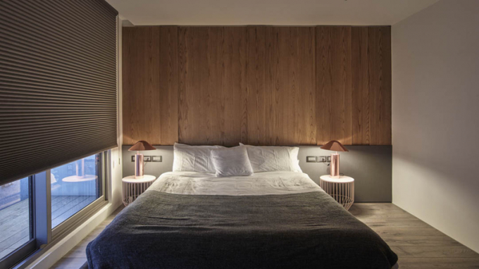 Phòng ngủ chính mang màu sắc ấm giống với phòng khách. Giấy dán tường bằng gỗ và đèn bàn tăng không khí yên tĩnh cho căn phòng.