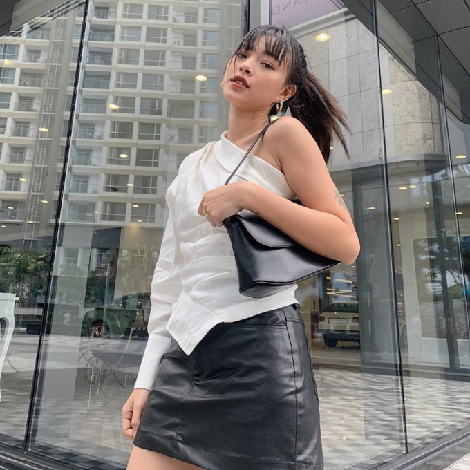 Tú Hảo để lộ vai trần gợi cảm với thiết kế blouse trắng lệch vai, mix cùng chân váy da và túi đeo ăn ý.