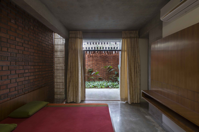 Phòng ngủ đơn giản nhưng mát mẻ nhờ bức tường gạch và khoảng sân vườn bên ngoài.