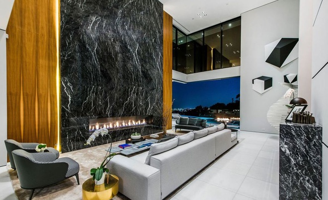 Phòng khách rộng lớn, sang trọng với điểm nhấn là một cái lò sưởi khổng lồ làm bằng đá. Những bức tường kính đem đến ánh sáng tự nhiên và cảnh quan bao quát của thành phố Los Angeles.