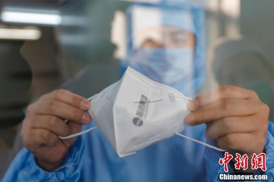 Công nhân ở Cáp Nhĩ Tân cầm trên tay chiếc khẩu trang y tế vừa hoàn thành. Một dây chuyền sản xuất mới được đưa vào hoạt động trở lại ở Cáp Nhĩ Tân sản xuất trung bình 30.000 khẩu trang N95, 20.000 khẩu trang phẫu thuật mỗi ngày. (Ảnh: China News)
