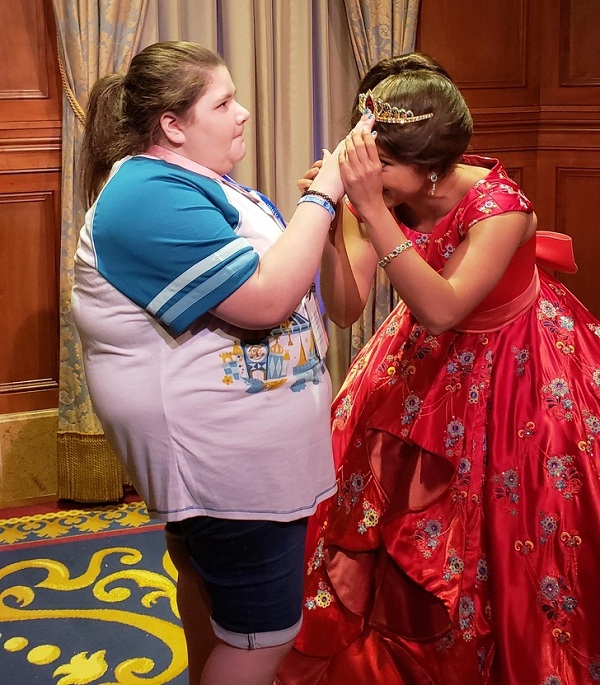 Công chúa Disney đang cúi đầu để một fan hâm mộ bị mù sờ và cảm nhận vương miện của cô ấy.